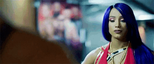 a woman with purple hair and a red top is standing next to a man .