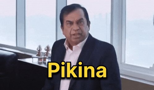 a man in a suit is sitting in front of a window and the word pikina is on the screen behind him