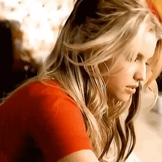 a woman with long blonde hair and a red shirt is looking down .