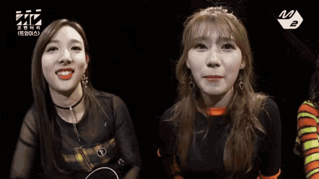 two girls are sitting next to each other and one of them is wearing earrings