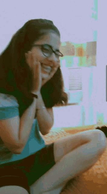 a woman wearing glasses is sitting on the floor laughing