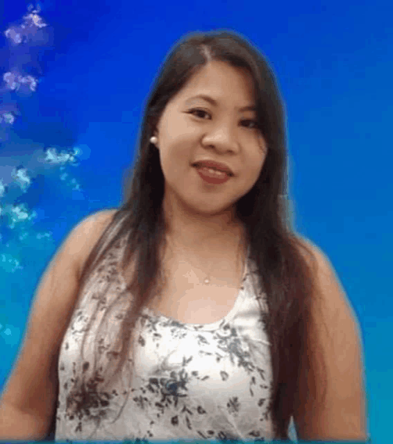 a woman with long hair is wearing a floral tank top and smiling .
