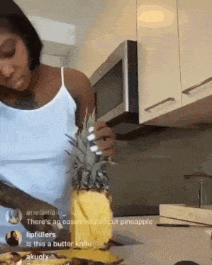 a woman is cutting a pineapple with a butter knife ..
