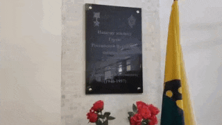 a plaque on a wall next to a vase of roses