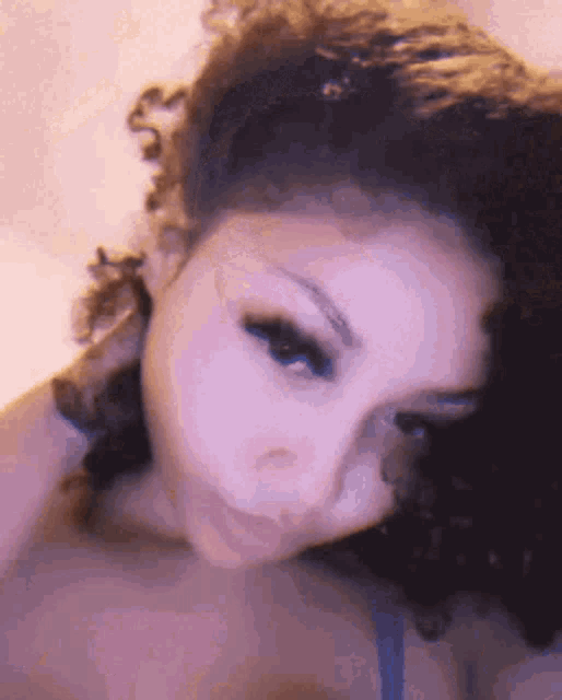 a close up of a woman 's face with her eyes closed and her hair in a ponytail .