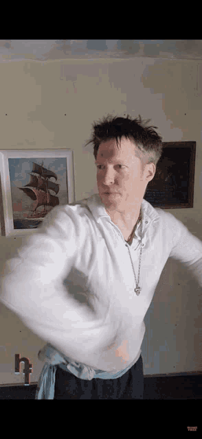 a man in a white shirt is standing in front of a painting of a sailboat