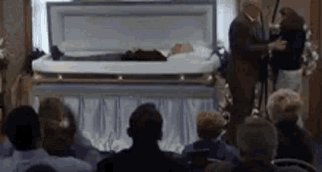 a group of people sitting in front of a coffin .
