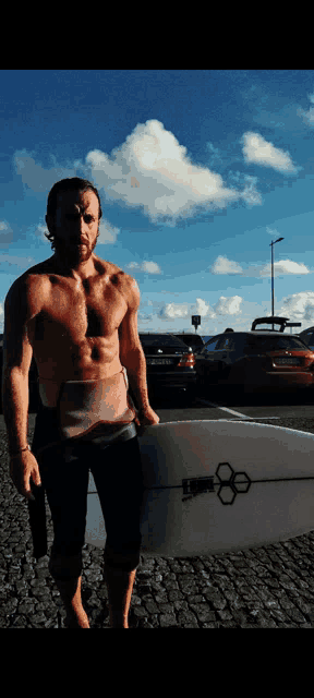 a shirtless man is holding a surfboard with a sticker on it that says ' ae '