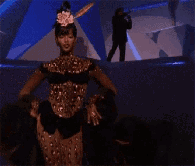 a woman in a leopard print dress is dancing in front of a crowd