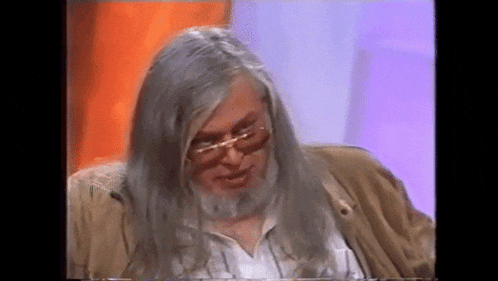 a man with long grey hair and a beard wears glasses