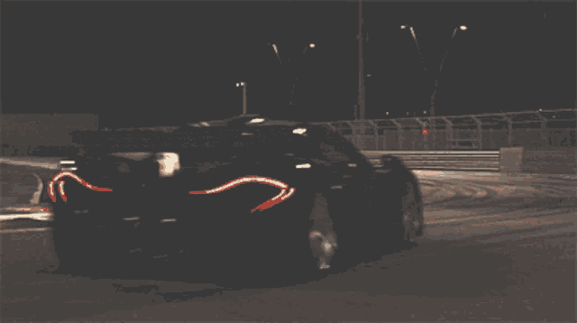 a car is drifting on a race track at night with a sign in the background that says rk rumble