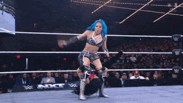 a woman with blue hair is wrestling another woman in a wrestling ring