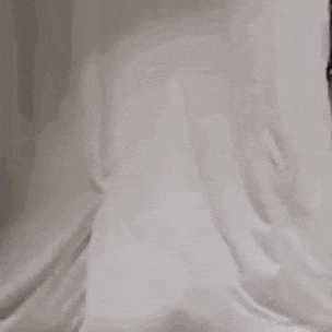 a person is sitting in a corner of a room with their head in a shower curtain .