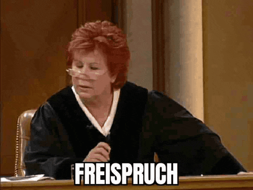 a female judge is sitting at a desk with the word freispruch written on her face