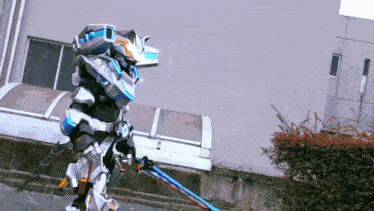 a person in a robot costume is holding two swords in front of a building