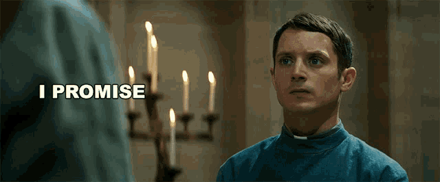 a man in a blue shirt is standing in front of candles and says i promise