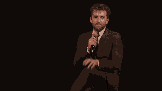 a man in a suit is holding a microphone in his hand