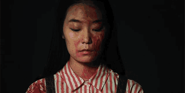 a woman with blood on her face is wearing a red and white striped shirt