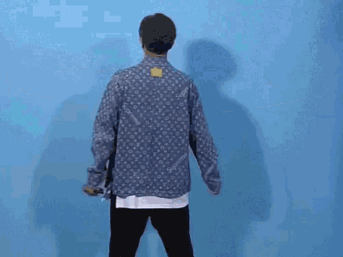 a man wearing a supreme shirt is dancing in front of a blue wall