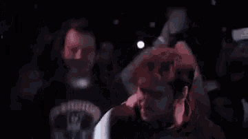 a group of people are dancing in a dark room at a concert .