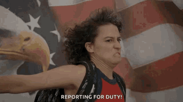 a woman is standing in front of an american flag with her arms outstretched and making a funny face .