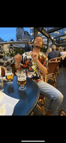 a man is sitting at a table with two glasses of beer