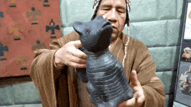a man is holding a statue of a cat with the letter s on it