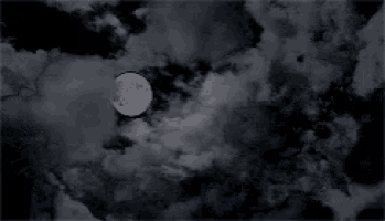 a black and white photo of a full moon in a cloudy sky .