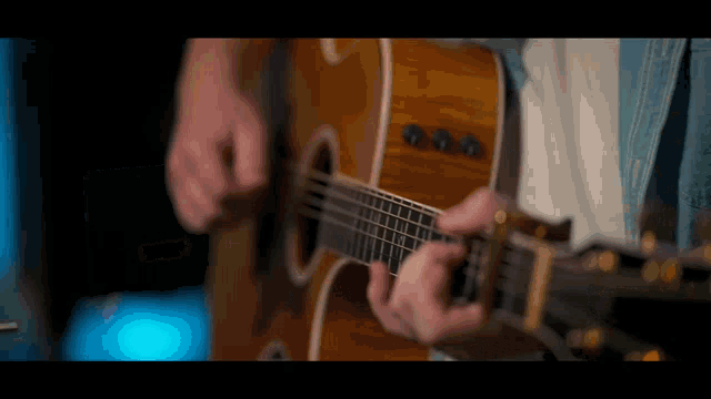 a person is playing an acoustic guitar in a dark room
