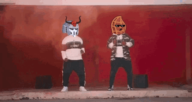 two men are standing next to each other on a sidewalk with their heads on robots .