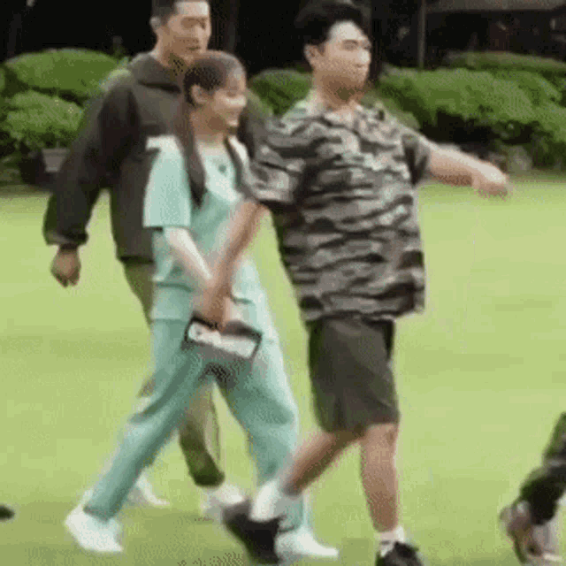 a group of people are walking on a lush green field holding hands .