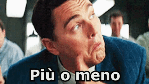 a man in a suit is making a funny face and the words più o meno are on the bottom of his face .