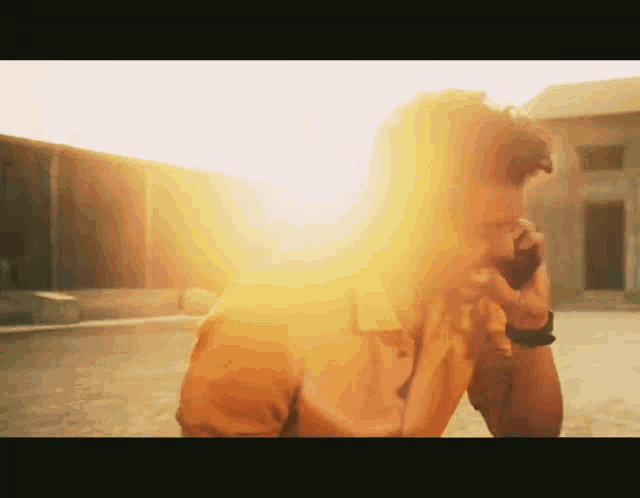 a man in a yellow shirt stands in front of a bright yellow light