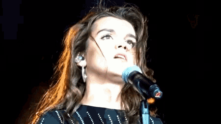 a close up of a woman singing into a microphone on a stage