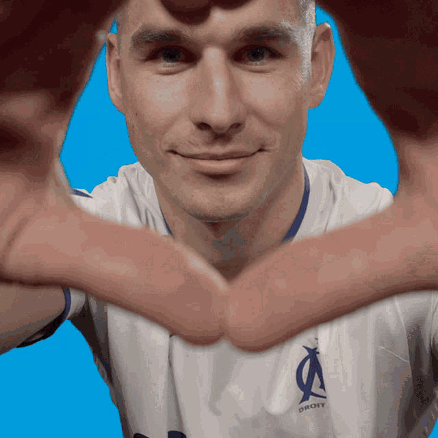 a man making a heart shape with his hands with a shirt that says droit on it
