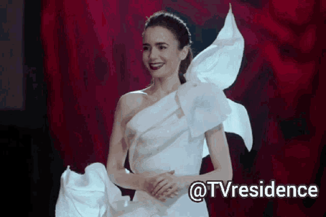 a woman in a white dress with a red background and the words @tvresidence below her