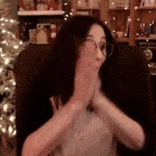 a woman is sitting in a chair with her hands on her face .