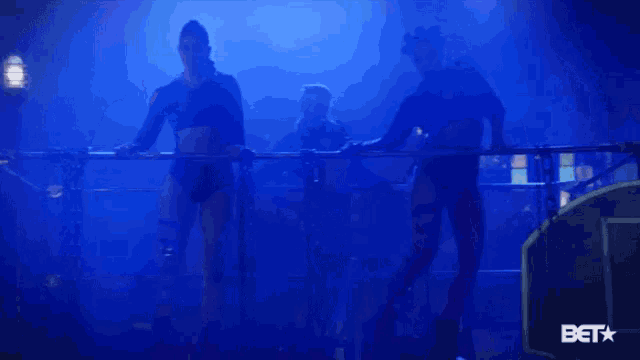 a group of women are dancing on a stage with a blue background .