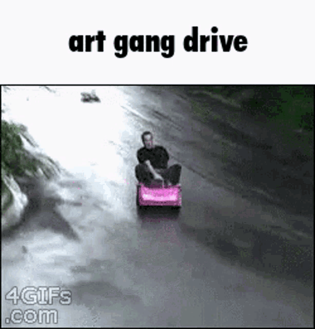 a man is riding a pink toy car down a street .