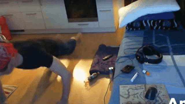 a person is doing push ups on the floor in front of a bed with headphones on it