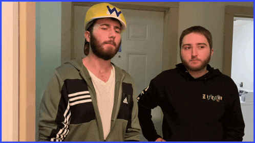 a man wearing an adidas jacket stands next to another man wearing a hoodie