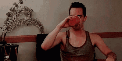 a man is drinking from a red cup while sitting in a chair .