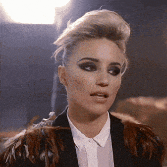 a woman wearing a black jacket with feathers on the shoulder