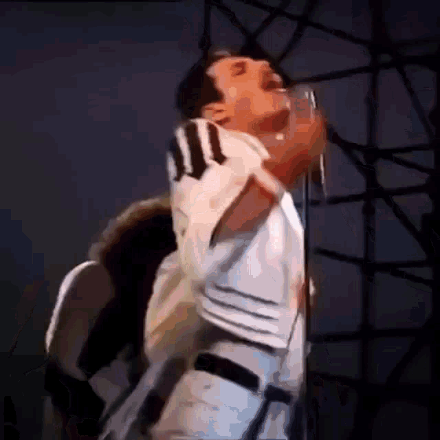 a man is singing into a microphone on a stage while wearing a striped shirt .