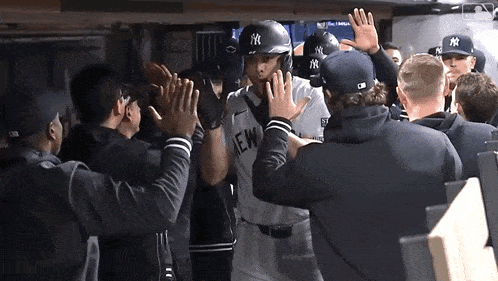 a new york yankees baseball player high fives his teammates in the dugout