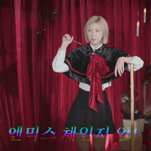 a woman in a cape stands in front of a red curtain with korean writing on it