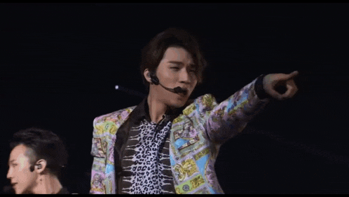 a man wearing a colorful jacket and a microphone pointing