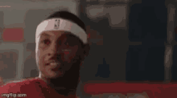 a man wearing a headband with a nba logo on it is looking at the camera .
