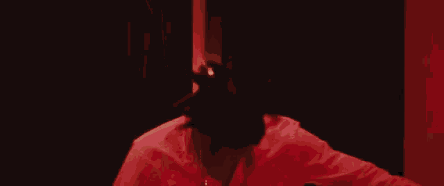 a woman in a red shirt is standing in front of a red light .