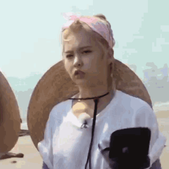a woman wearing a pink headband and a hat is standing on a beach .